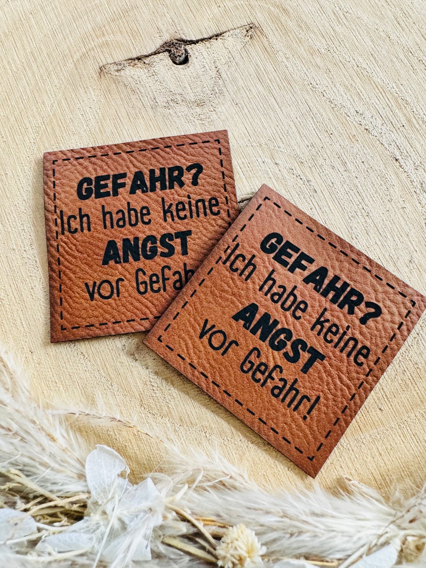 braunes Kunstleder Label mit dem Spruch Gefahr Fragezeichen Ich habe keine Angst vor gefahr ausrufezeichen in schwarzer schrift