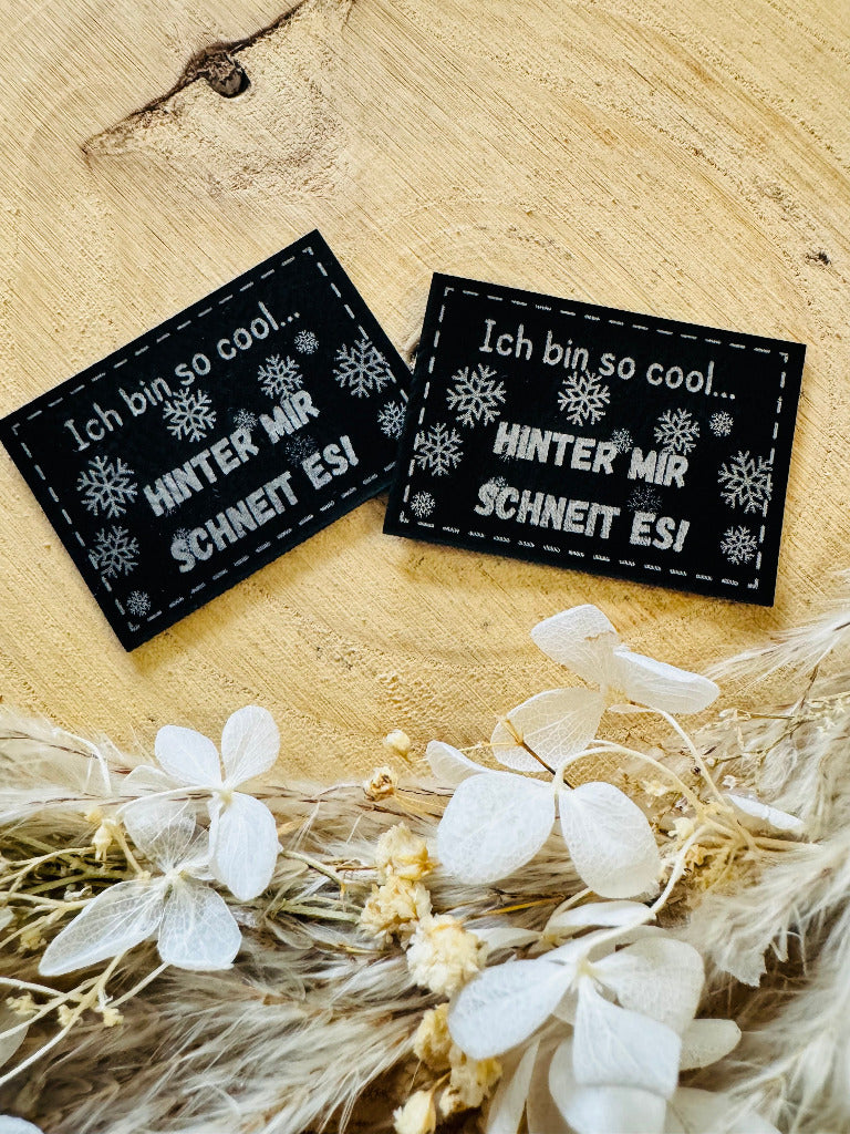 superweiches schwarzes Kunstlederlabel mit dem Spruch Ich bin so cool Punkt punkt Hinter mir schneit es Ausrufezeichen mit kleinen Schneekristallen in silberner Schrift