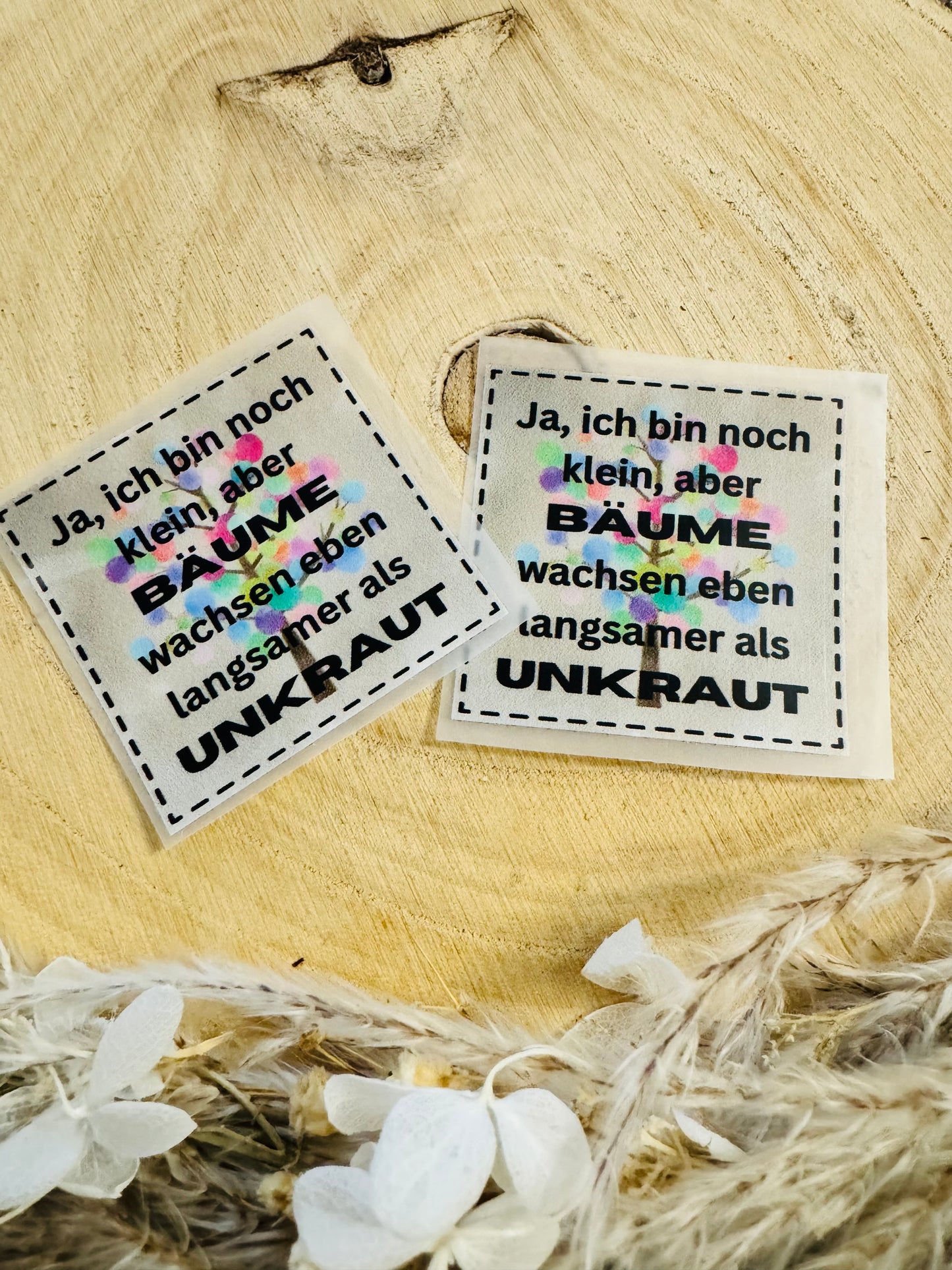Bügellabel mir dem Spruch Ja, ich bin noch klein, aber Bäume wachsen eben langsameer als Unkraut mit einem bunten Bäumchen im Hintergrund