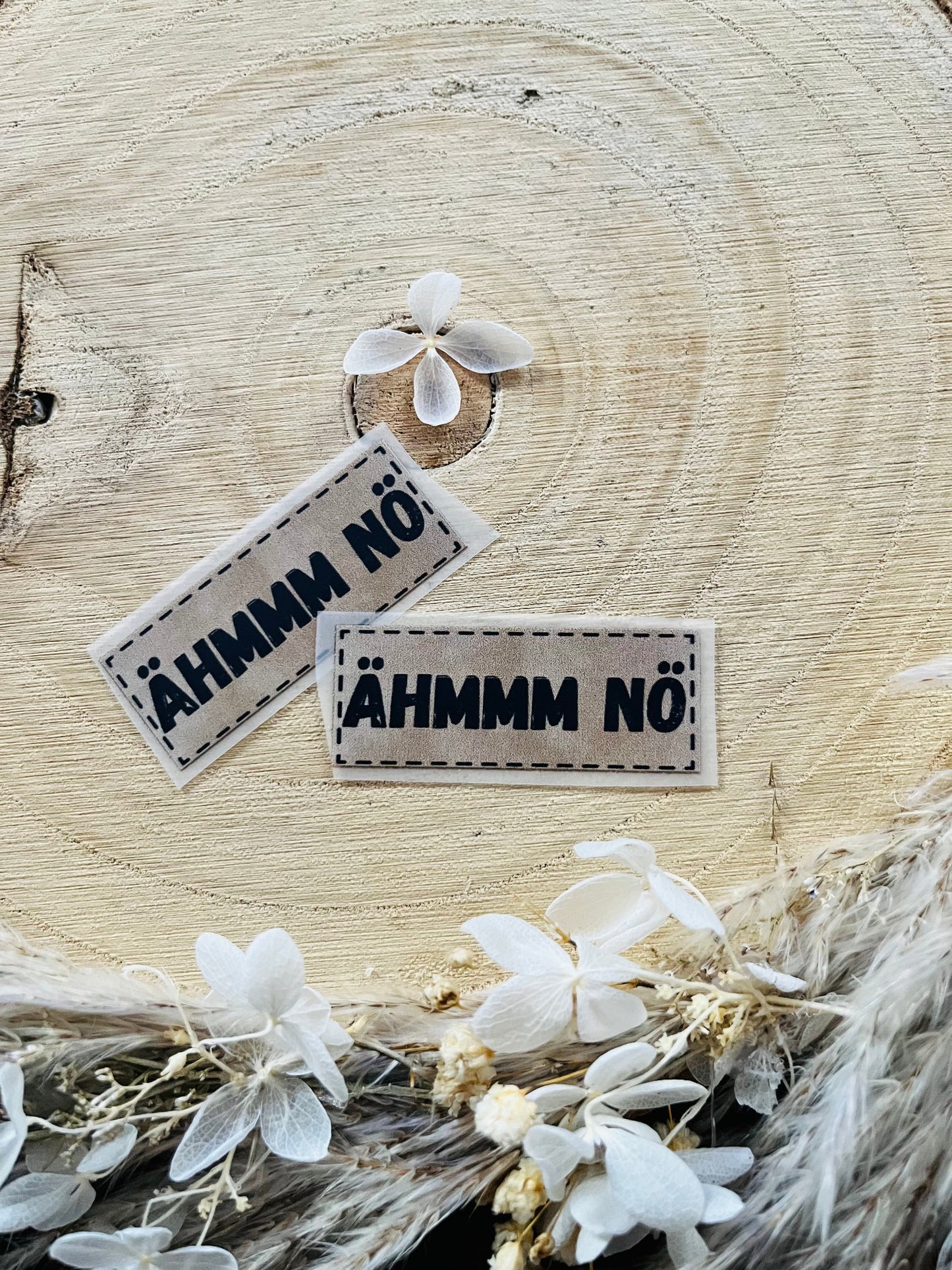 hellgraues Bügellabel mit dem Spruch ÄHMMM NÖ in schwarzer Schrift
