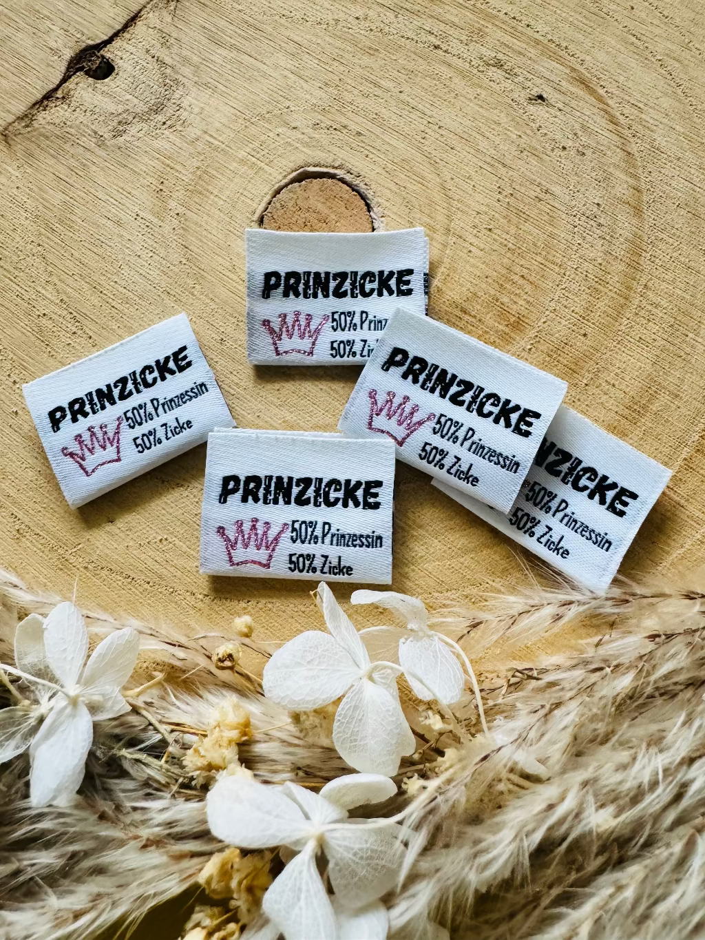 weisses Weblabel mit dem Spruch Prinzicke 50 Prozent Prinzessin 50 Prozent Zicke in schwarzer Schrift mit einer roten Krone