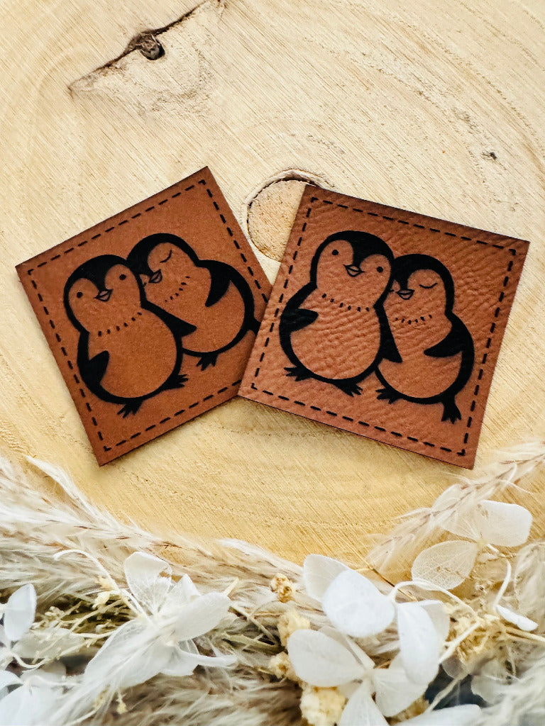 superweiches braunes Kunstlederlabel mit zwei kuschelnden kleinen Pinguinen