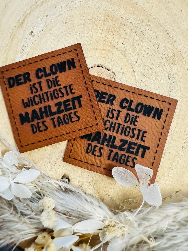 superweiches braunes Kunstlederlabel mit dem Spruch Der Clownist die wichtigste Mahlzeit des Tages