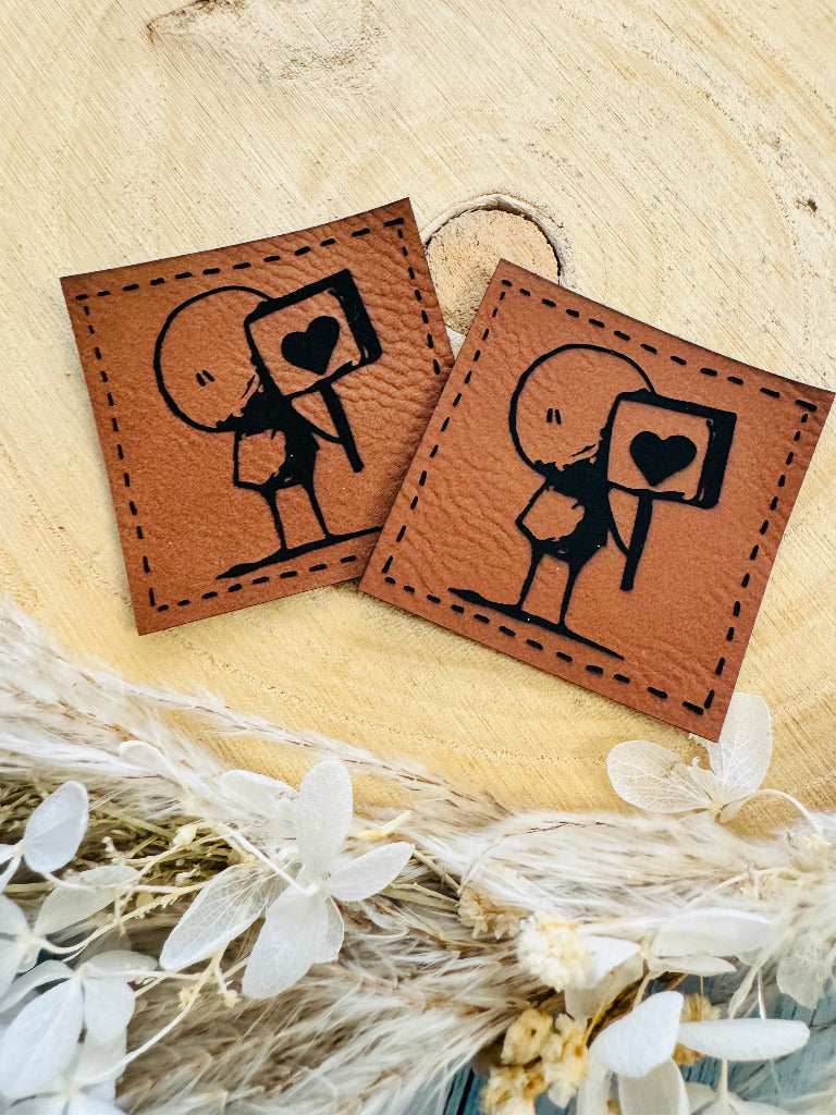 superweiches braunes Kunstlederlabel mit einem kleinen Kameramannund einem Herzchen abgebildet