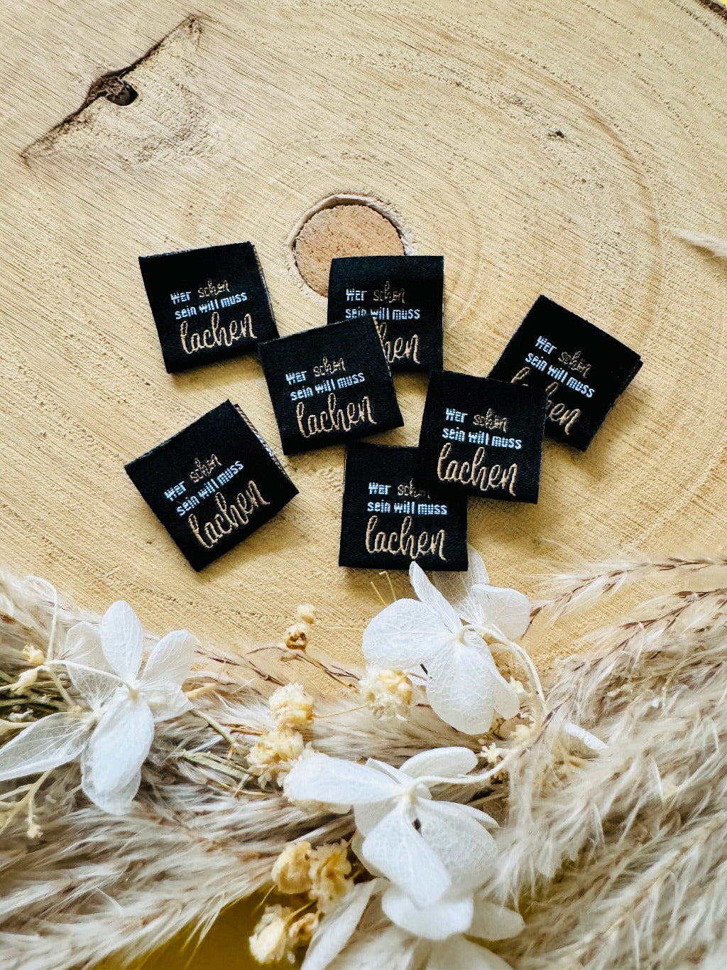 schwarzes Weblabel mit dem Spruch wer schön sein will muss lachen in weiss bronzener Schrift