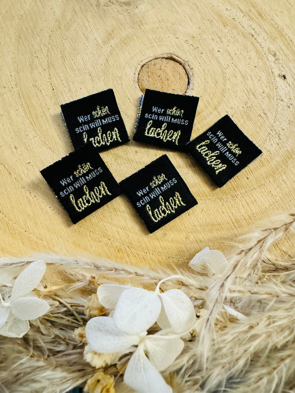 schwarzes Weblabel mit dem Spruch wer schön sein will muss lachen in weiss goldener Schrift