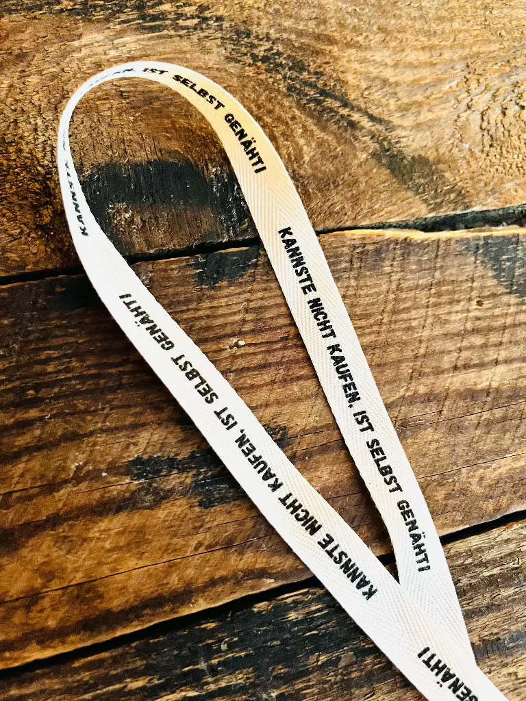 Baumwoll Webband mit Spruch Kannste nicht kaufen, ist selbst genaeht auf weißem Untergrund