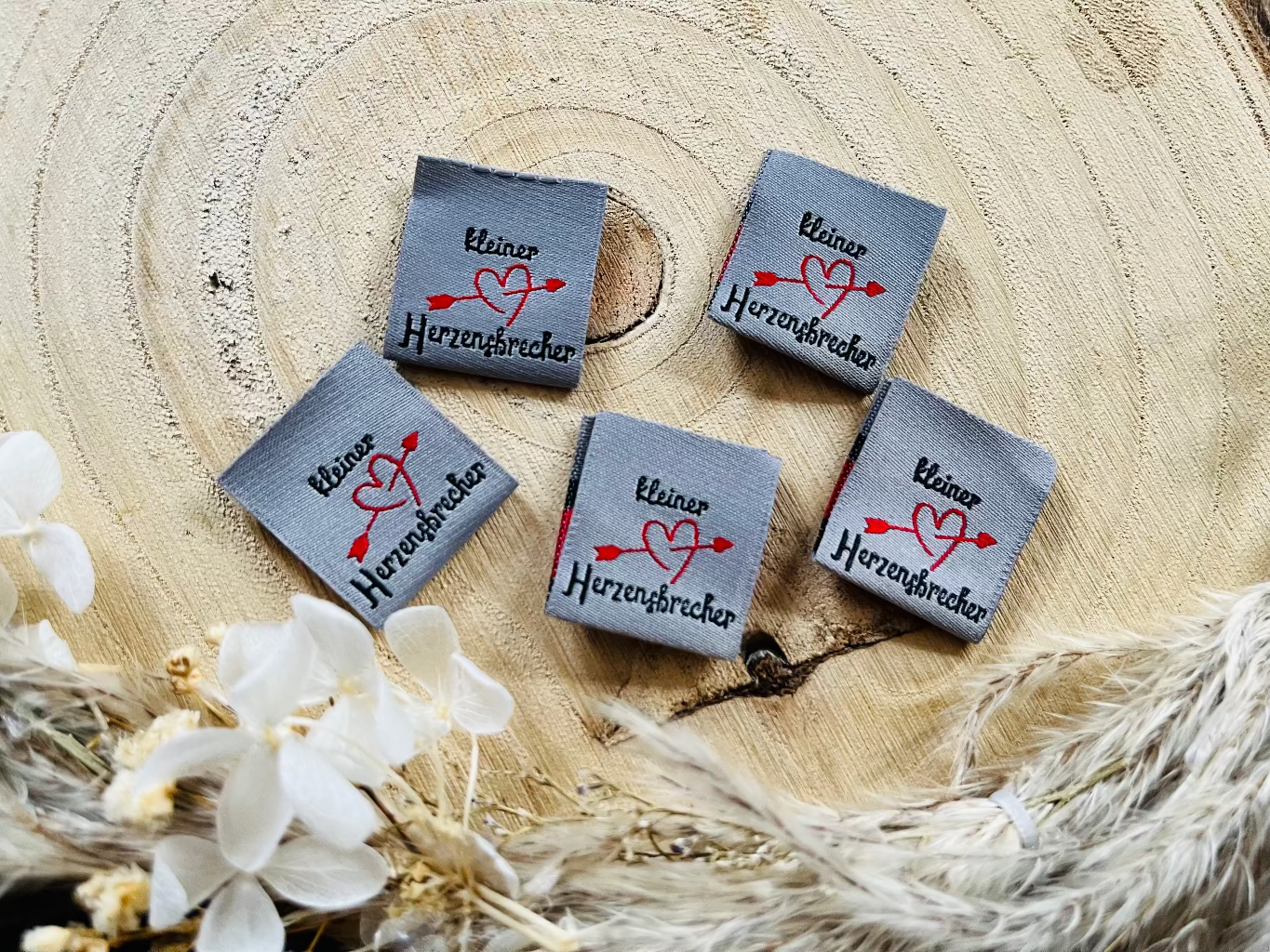 hellgraues Weblabel mit dem Spruch kleiner herzensbrecher in schwarzer Schrift und einem Herz mit Pfeil in rot