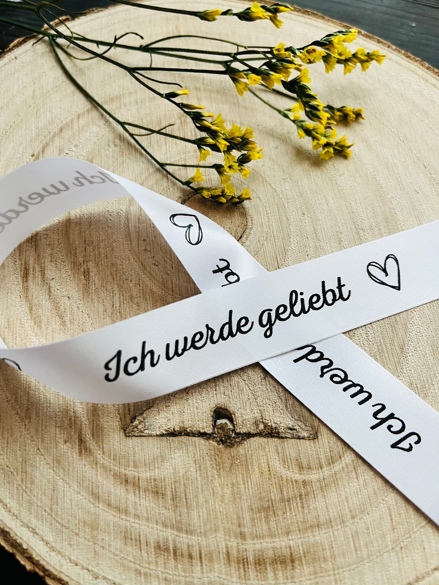 weisses Satinband mit dem fortlaufenden Spruch Ich werde geliebt und kleinen Herzen, Breite zwei Zentimeter.