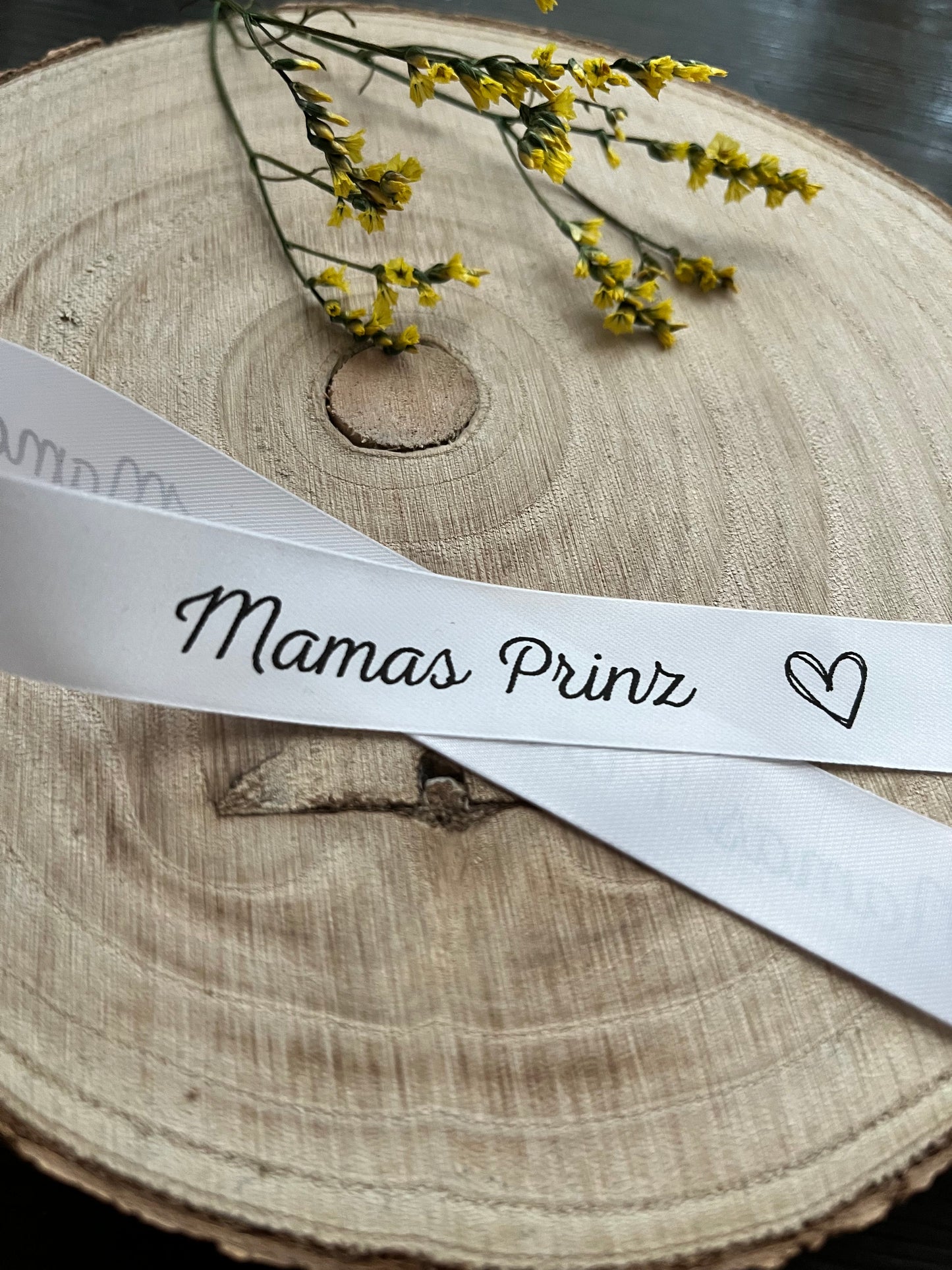weisses Satinband mit dem fortlaufenden Spruch Mamas Prinz und kleinen Herzen