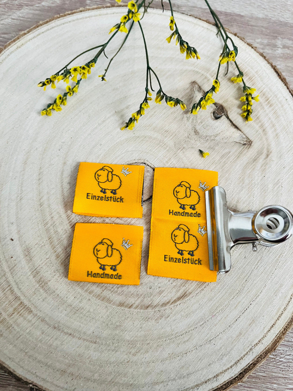 gelbes Weblabel mit einem kleinen Schäfchen und dem Spruch Einzelstück auf der einen und Handmade auf der anderen Seite in schwarz