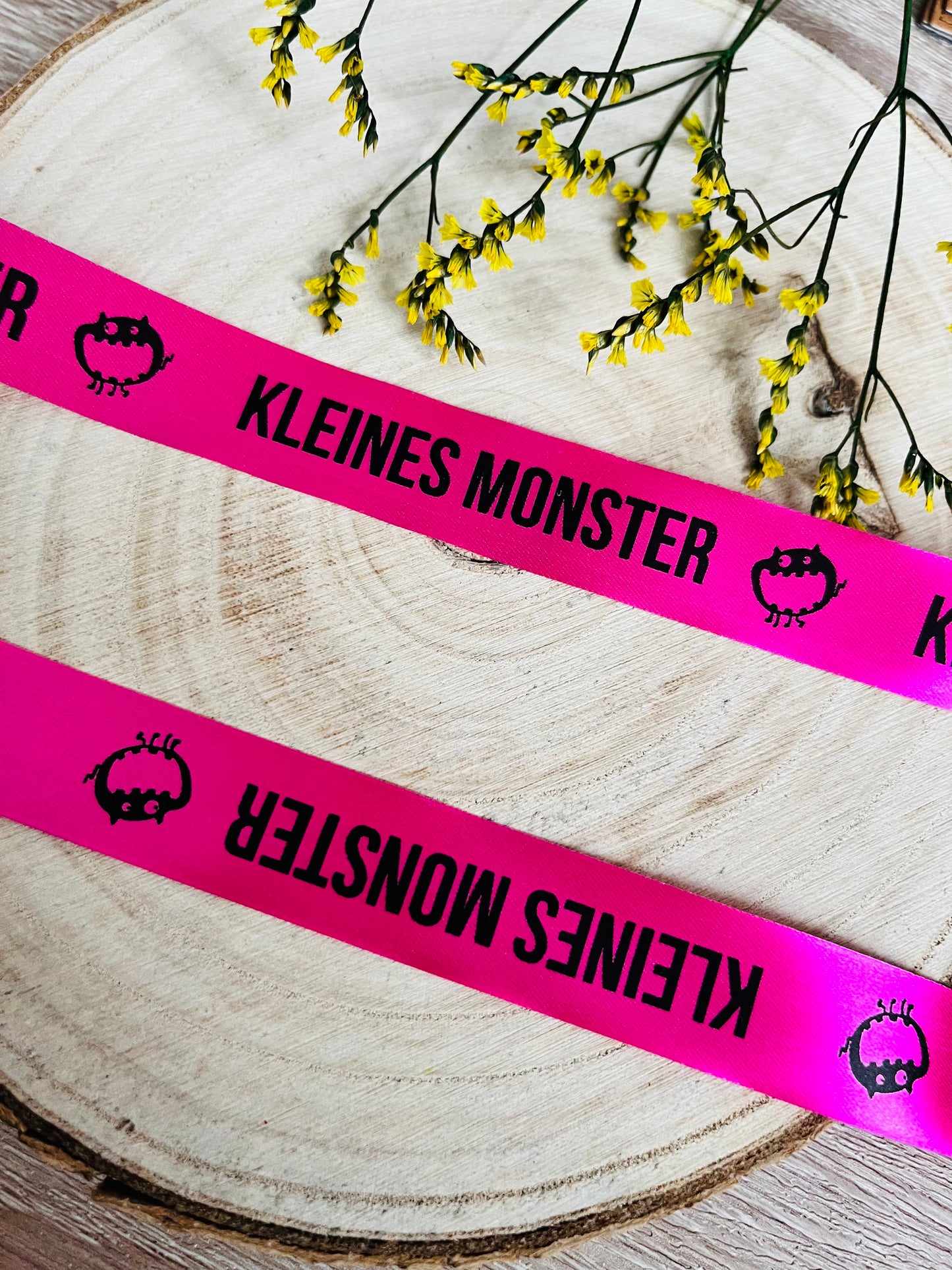 pinkfarbenes Satinband mit dem fortlaufenden Spruch Kleines Monster
