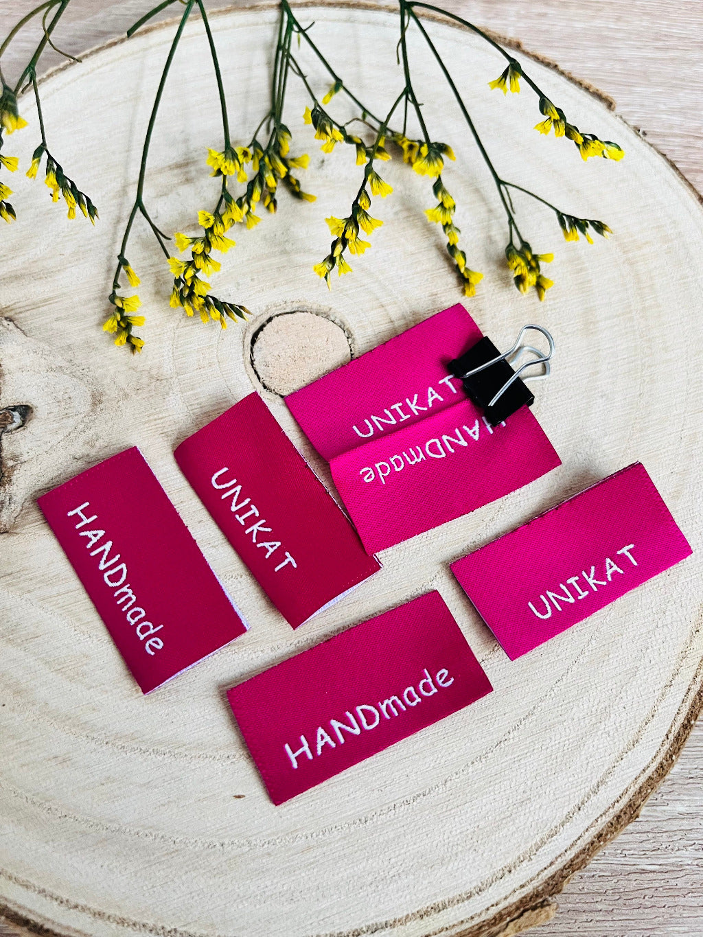 pinkfarbenes Weblabel mit dem Spruch Unikat und handmade auf je einer Seite in weisser Schrift
