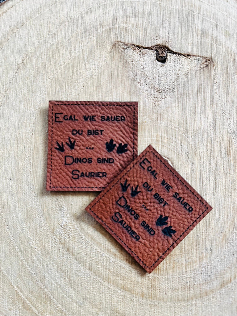 braunes Kunstlederlabel mit dem Spruch Egal wie sauer du bist Komma Dinos sind Saurier
