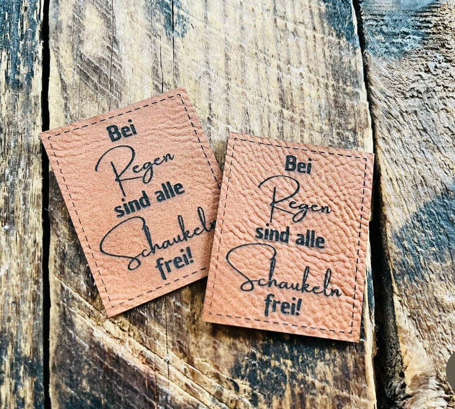 braunes PU-Label mit dem Spruch Bei Regen sind alle Schaukeln frei Ausrufezeichen