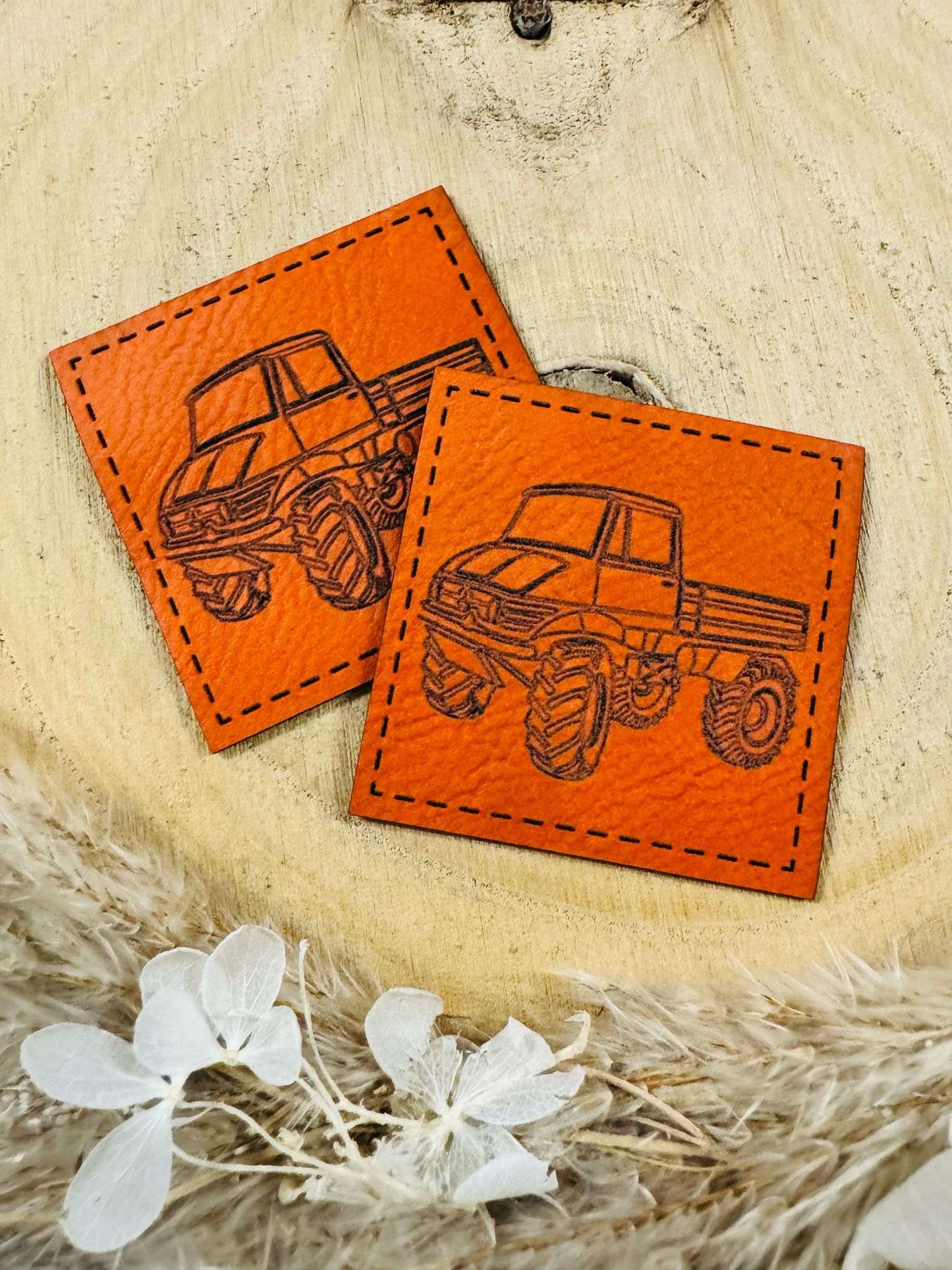 exclusives superweiches orangenes Kunstlederlabel mit einem Geände Laster abgebildet