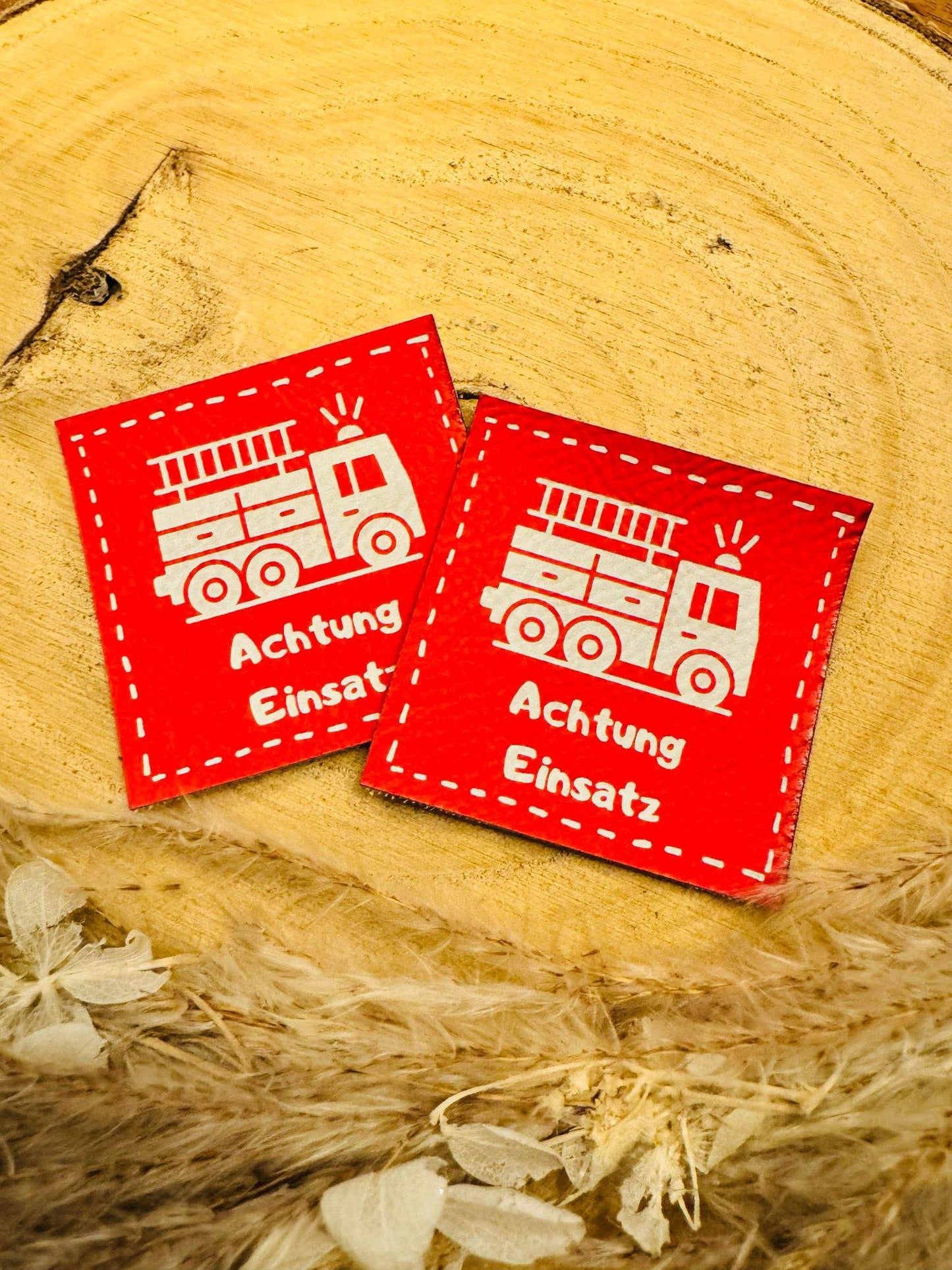 exclusives superweiches Kunstlederlabel in Rot mit einer Feuerwehr abgebildet und dem Spruch Achtung Einsatz