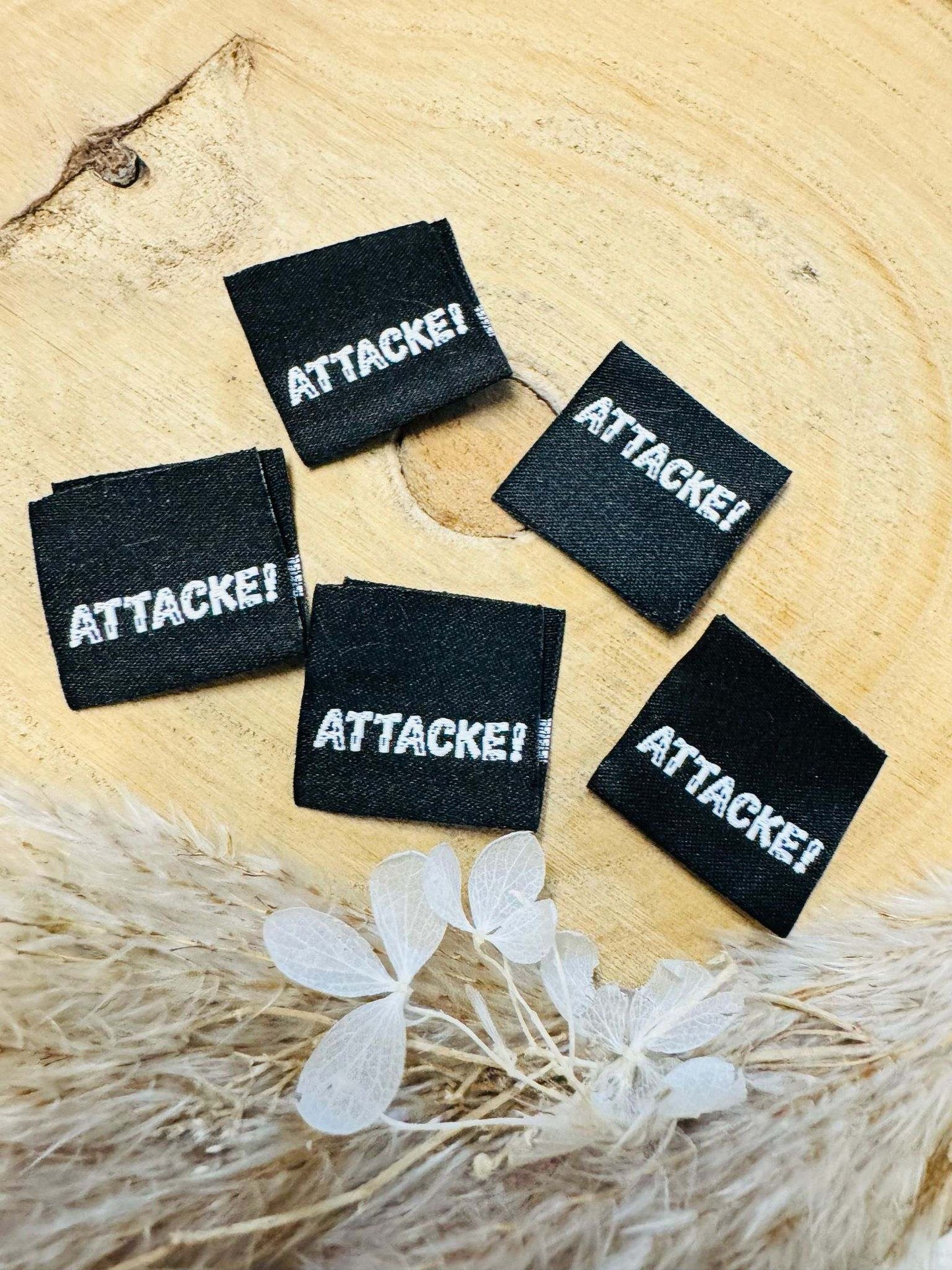 exclusives schwarzes Weblabel aus Baumwolle mit dem Spruch Attacke Ausrufezeichen abgebildet