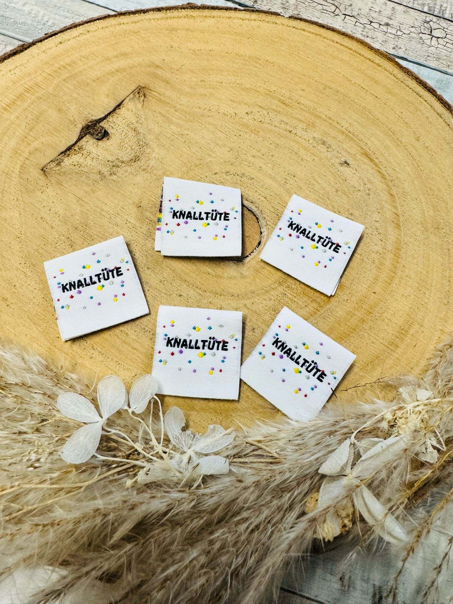 exclusives weisses Weblabel mit dem Spruch Knalltuete in schwarzer Schrift mit bunten Punkten