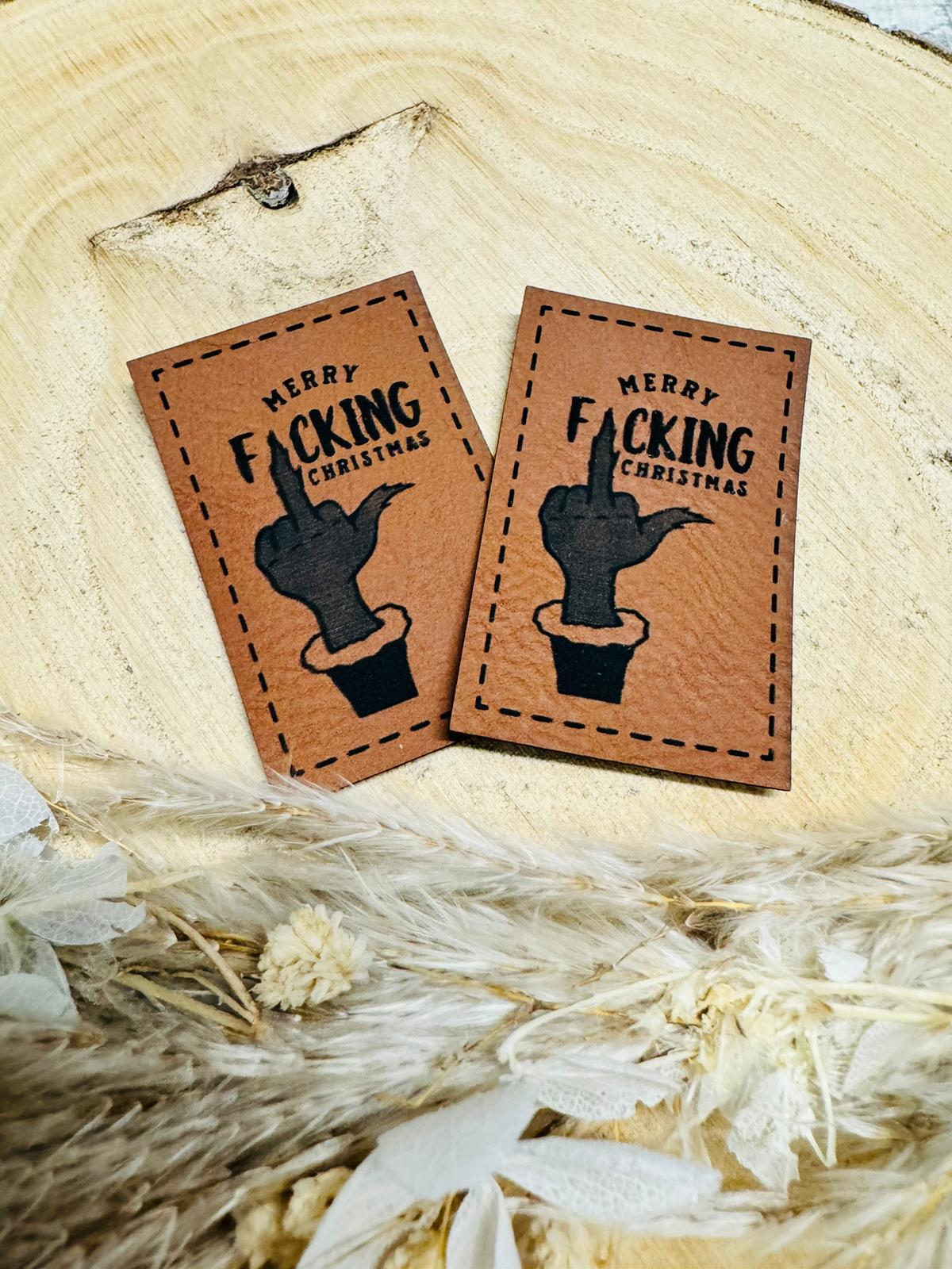 braunes christmas kunstlederlabel mit dem spruch merry fucking christmas und einem stinkefinger