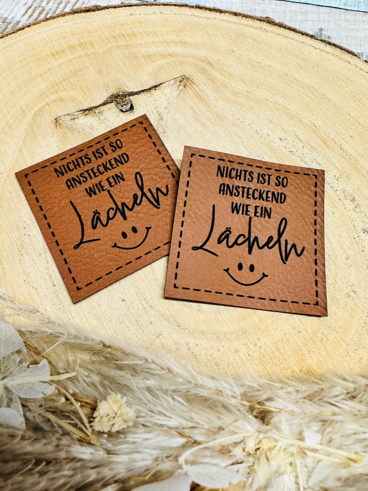 braunes christmas kunstlederlabel mit dem spruch nichts ist so ansteckend wie ein kächeln und einem smiley