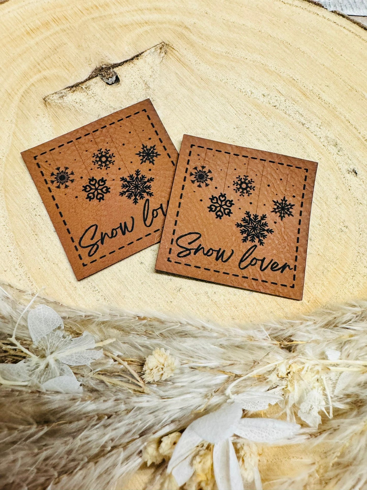 braunes christmas kunstlederlabel mit dem spruch snow lover und schneekristallen abgebildet