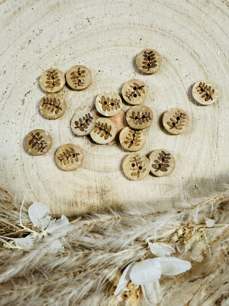 kleiner runder kokos Knopf mit einem Blattzweig abgebildet