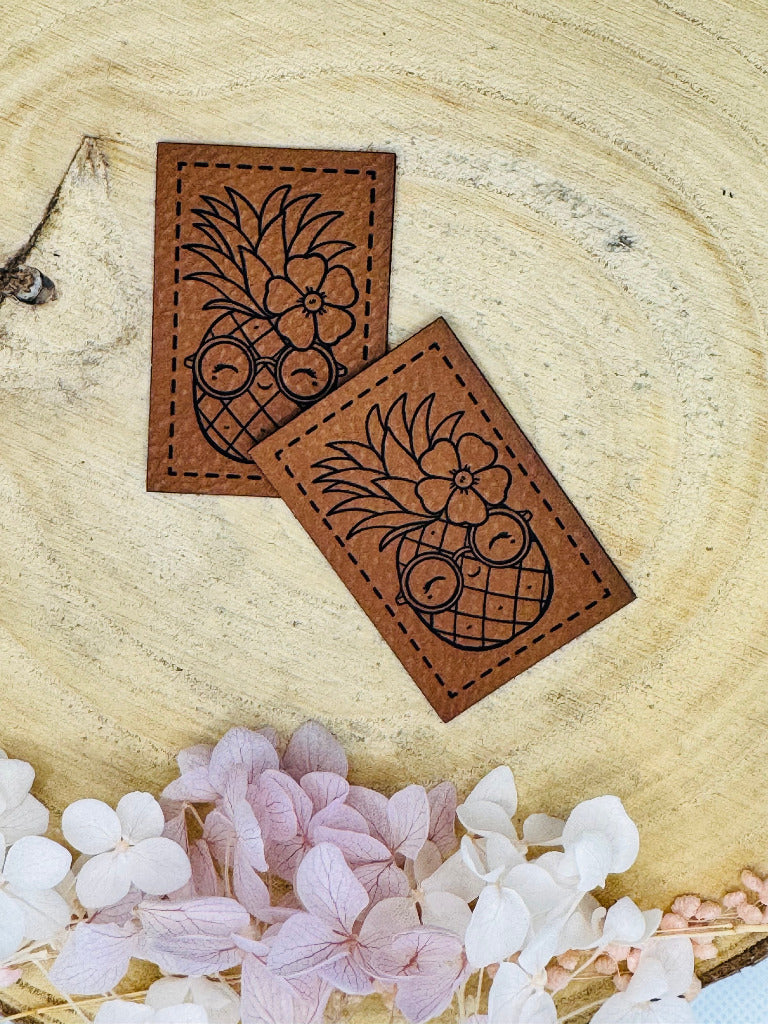 superweiches braunes Kunstlederlabel mit einer Ananas mit Blume abgebildet