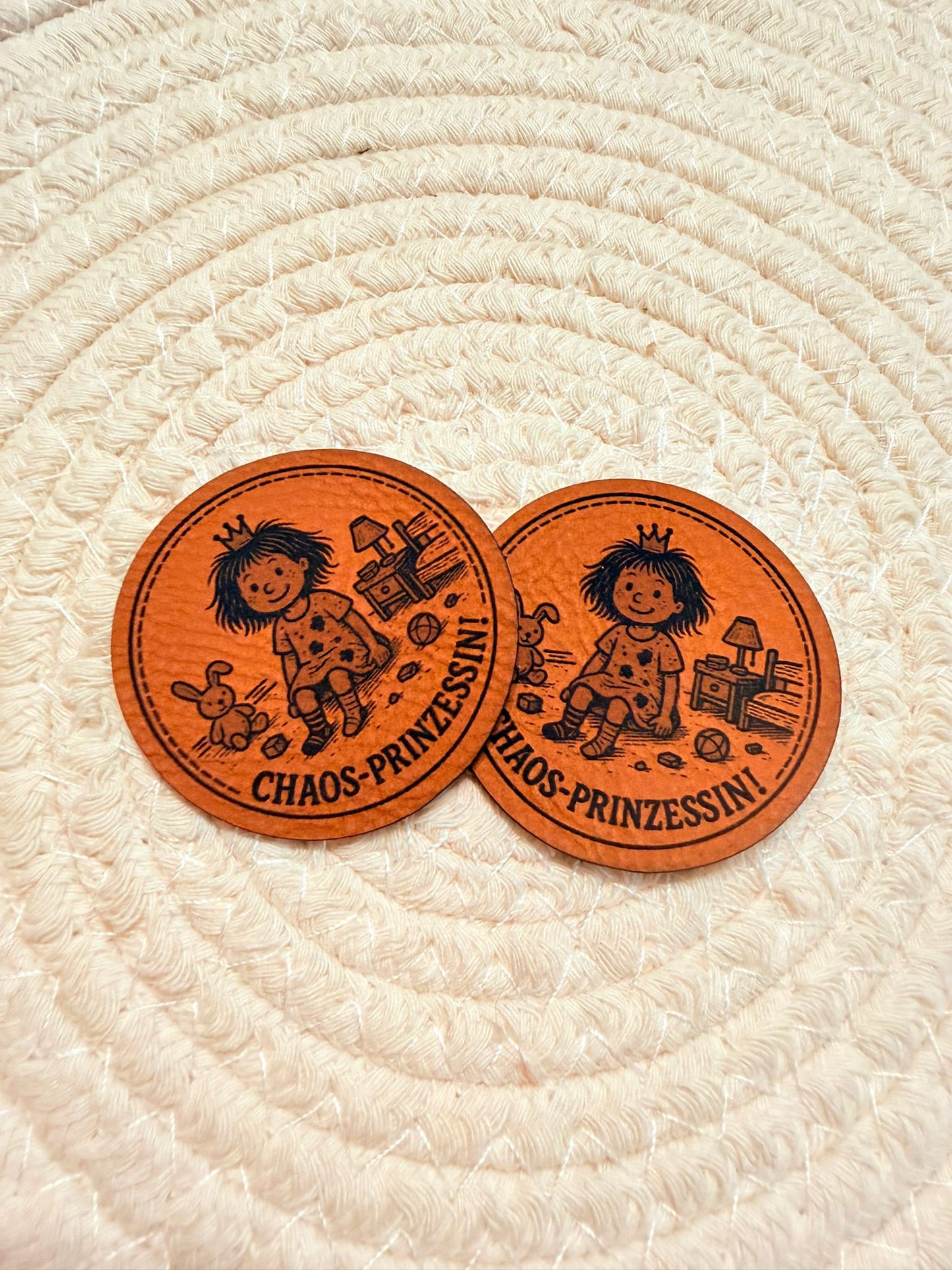 superweiches rundes braunes Kunstlederlabel mit dem Spruch Chaos Prinzessin und einem kleinen Mädchen inmitten seiner Spielzeug Welt sitzend