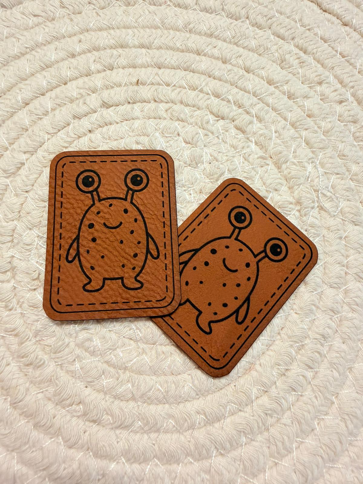 superweiches braunes Kunstlederlabel mit einem zweiäugigen Monsterchen