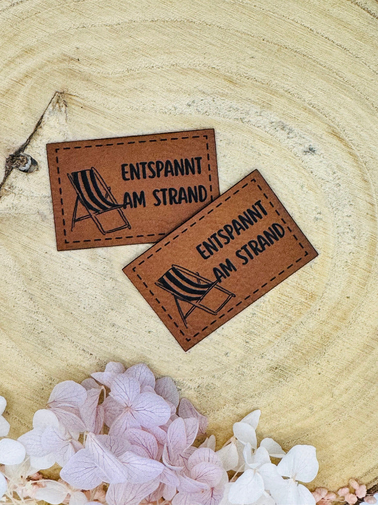 superweiches braunes Kunstlederlabel mit dem Spruch Entspannt am Strand und einem abgebildeten Liegestuhl