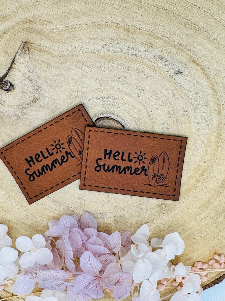 superweiches braunes Kunstlederlabel mit dem Spruch Hello Summer und abgebildeten Surfbrettern