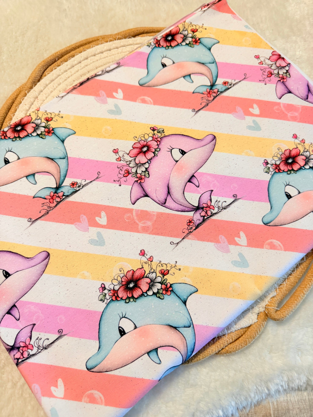 schöner Stoff mit kleinen rosa und blauen Delphinen mit Blumenschmuck auf rosa gelb weissem gestreiftem Untergrund