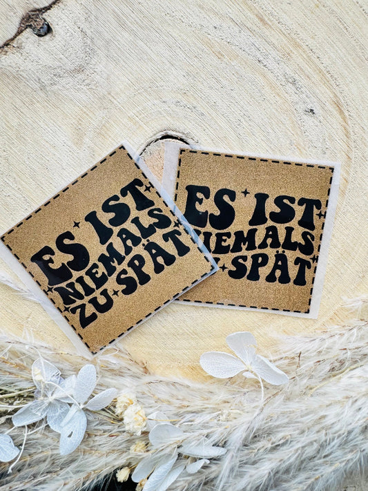 braunes Bügellabel Etikett mit dem Sruch Es ist niemals zu spät in schwarzer Schrift