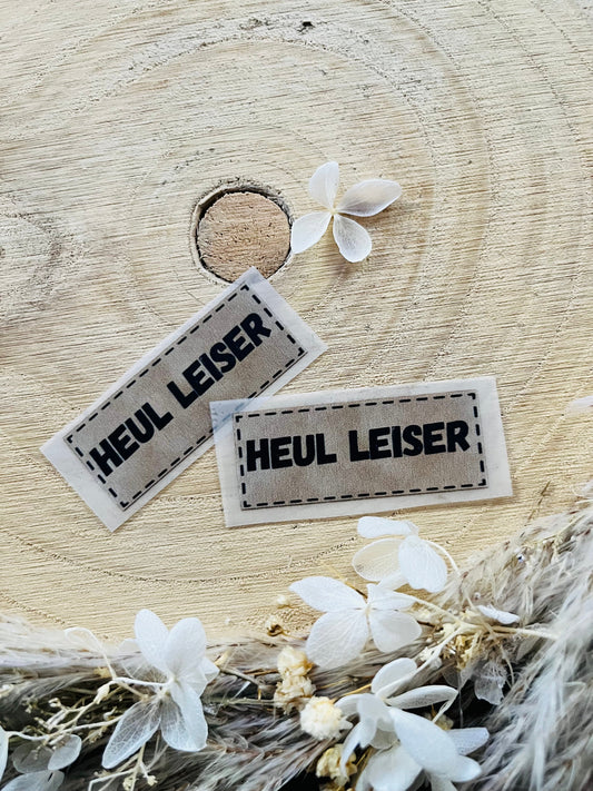 hellgraues Bügellabel mit dem Spruch Heul Leiser in schwarzer Schrift