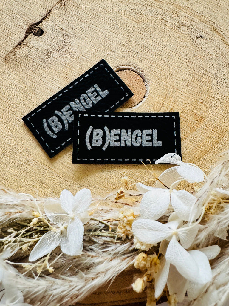 superweiches schwarzes Kunstlederlabel mit dem Spruch B in Klammern und Engel