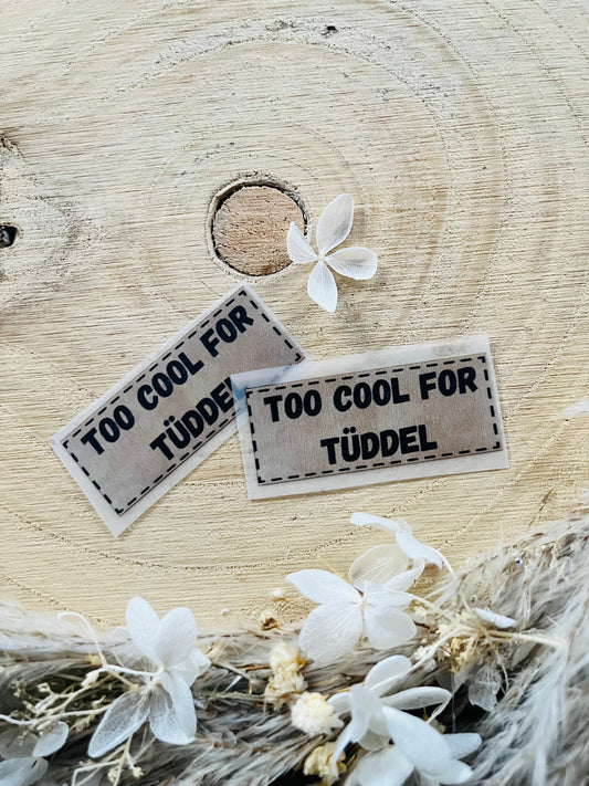 hellgraues Bügellabel mit dem Spruch Too cool for Tüddel 