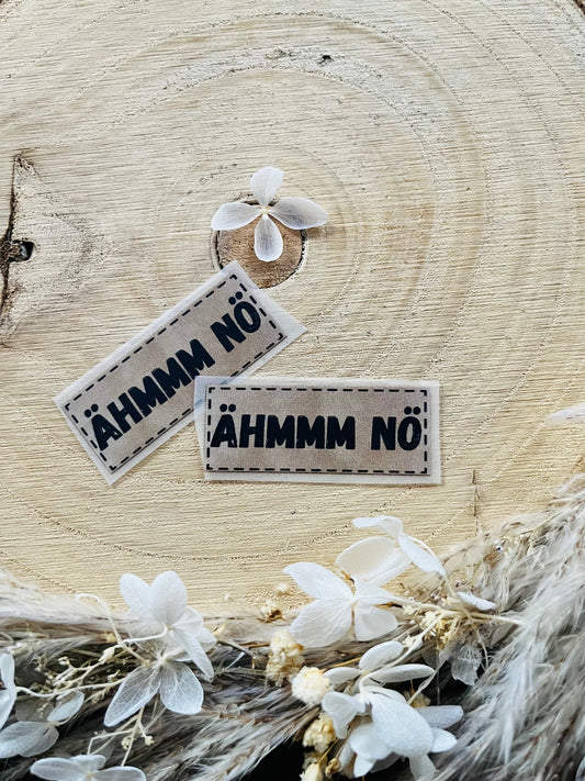 hellgraues Bügellabel mit dem Spruch ÄHMMM NÖ in schwarzer Schrift