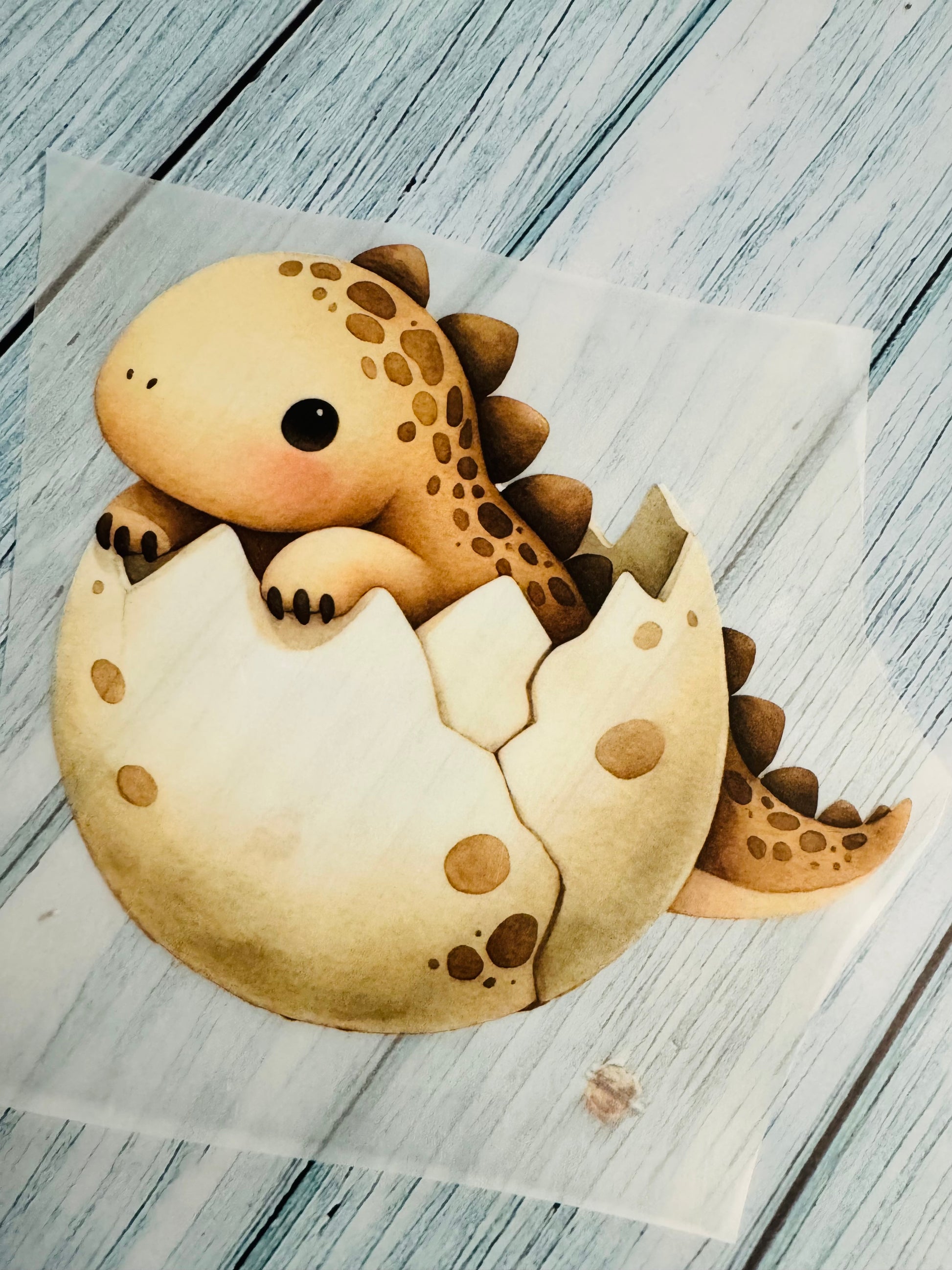 im Dunkeln leuchtendes Bügelbild mit einem kleinen aus einem Ei schlüpfenden Dino