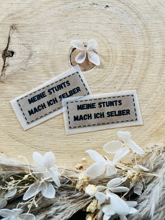 hellgraues Bügellabel mit dem Spruch Meine Stunts mach ich selber