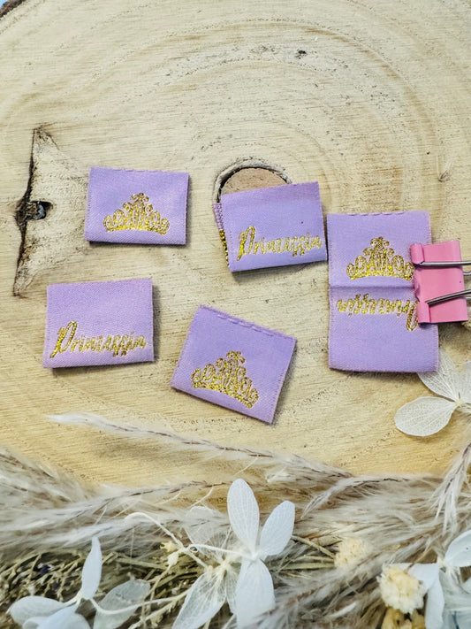 violettes Weblabel mit dem Spruch Prinzessin und auf der anderen Seite eine Krone in goldener Schrift