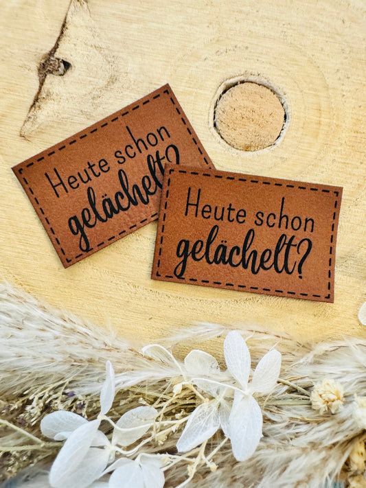 superweiches braunes Kunstlederlabel mit dem Spruch Heute schon gelächelt Fragezeichen