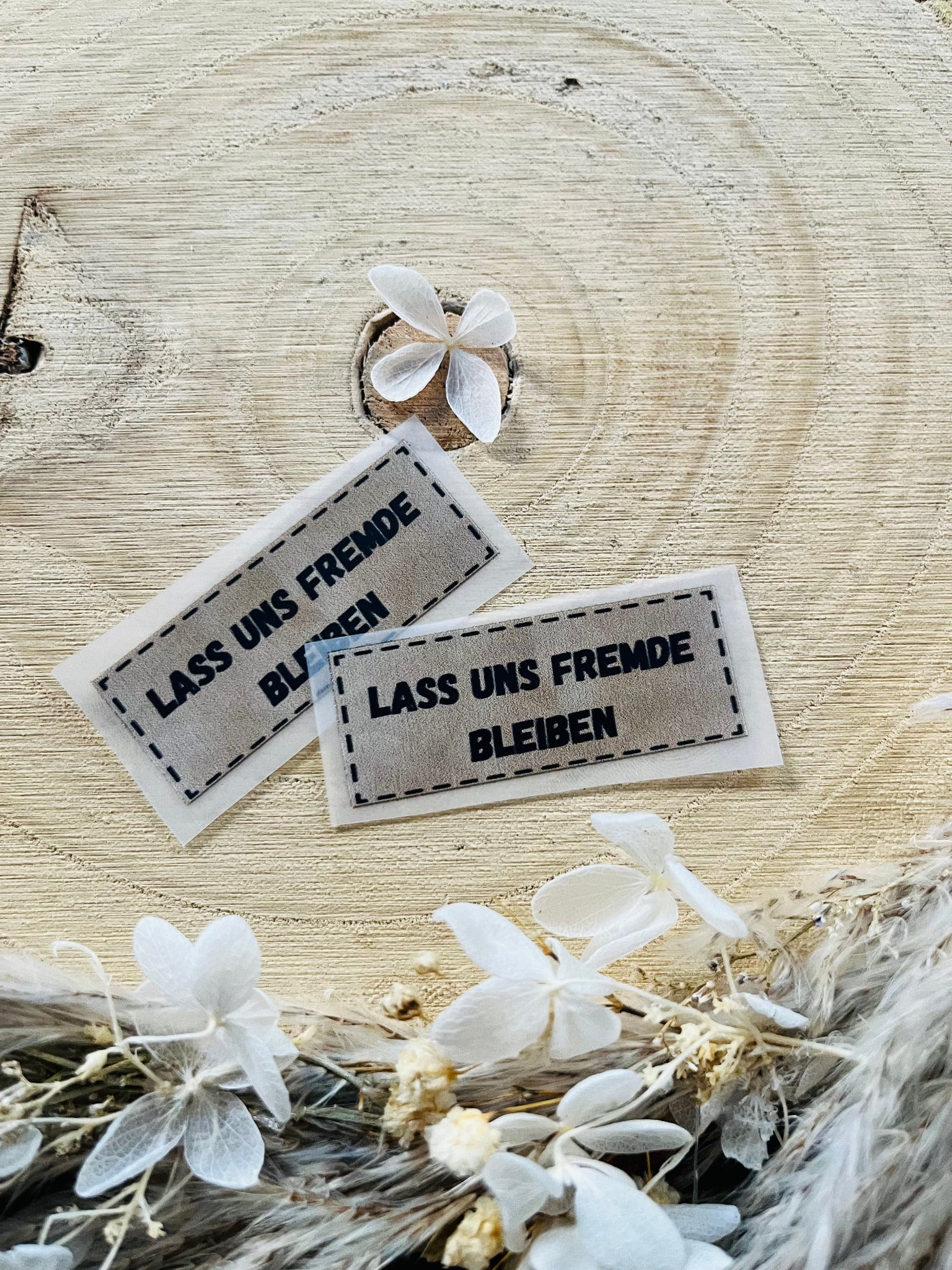 hellgraues Bügellabel mit dem Spruch Lass uns Frmde bleiben