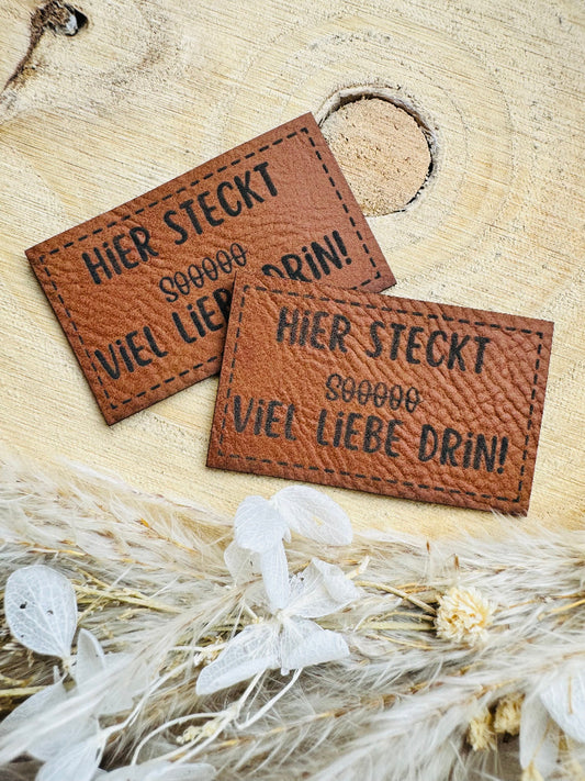 superweiches braunes Kunstlederlabel mit dem Spruch Hier stekt Soooo in Klammern Durchgestrichen viel Liebe drin Ausrufezeichen