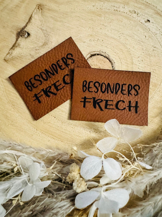 superweiches braunes Kunstlederlabel mit dem Spruch Besonders Frech in schwarzer Schrift