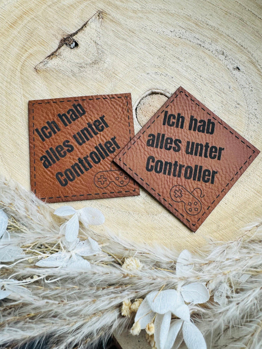 superweiches braunes PU-Label mit dem Spruch Ich hab alles unter Controller und einer abgebildeten Console