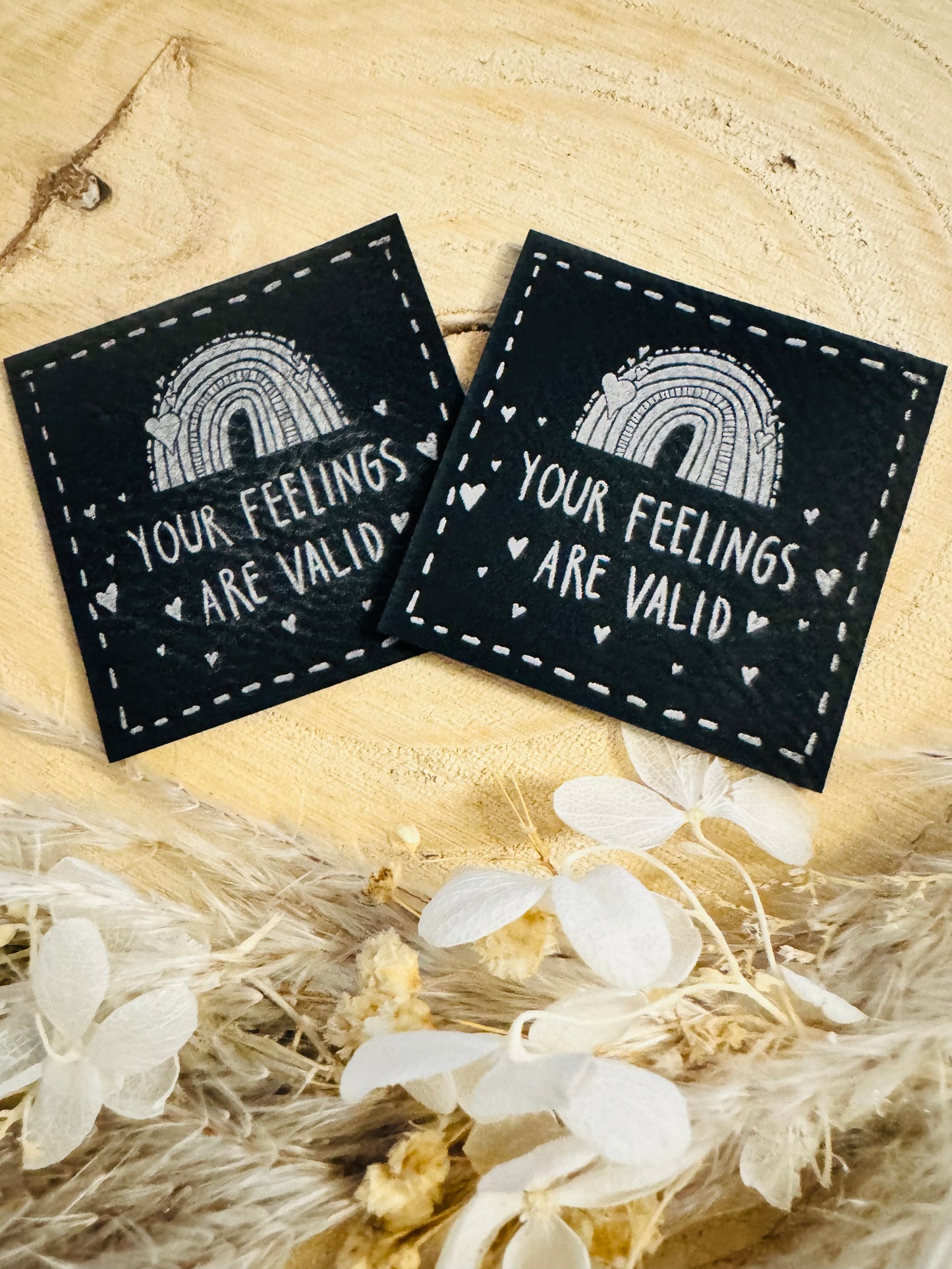 schwarzes kunstlederlabel mit dem spruch your feelings are valid und einem regenbogen abgebildet