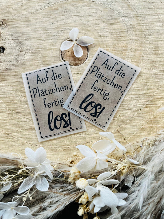 hellgraues Bügellabel mit dem Spruch Auf die Plätzchen ferig los Ausrufezeichen