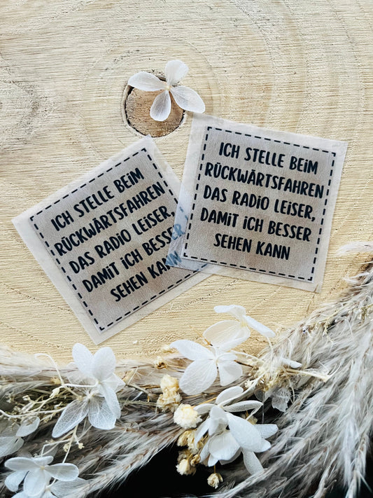 hellbraunes Bügellabel mit dem Spruch Ich stelle beim Rückwärtsfahren das Radio leiser, damit ich besser sehen kann