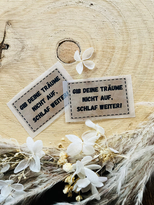 hellbraunes Bügellabel mit dem Spruch Gib deine Träume nicht auf, schlaf weiter Ausrufezeichen in schwarzer Schrift